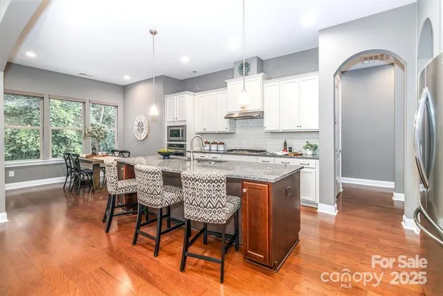 a kitchen with stainless steel appliances granite countertop dining table chairs sink and cabinets