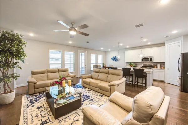a living room with furniture kitchen view and a large window