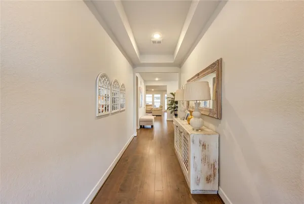 a view of a hallway to a livingroom with wooden floor and furniture