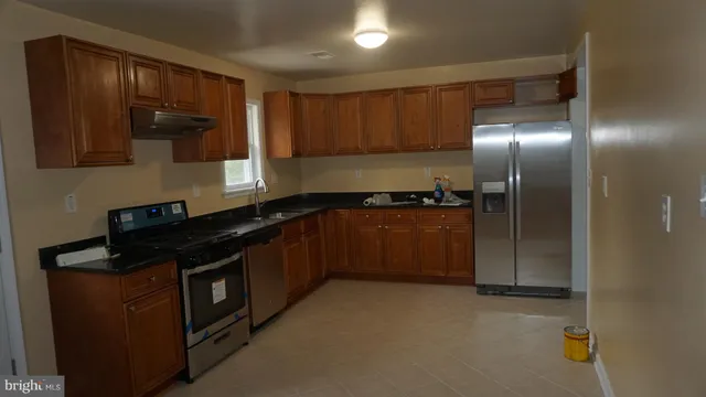 a kitchen with stainless steel appliances granite countertop a refrigerator and a stove top oven