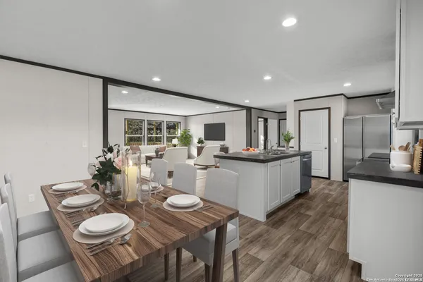 a kitchen with stainless steel appliances kitchen island granite countertop a table chairs and a refrigerator