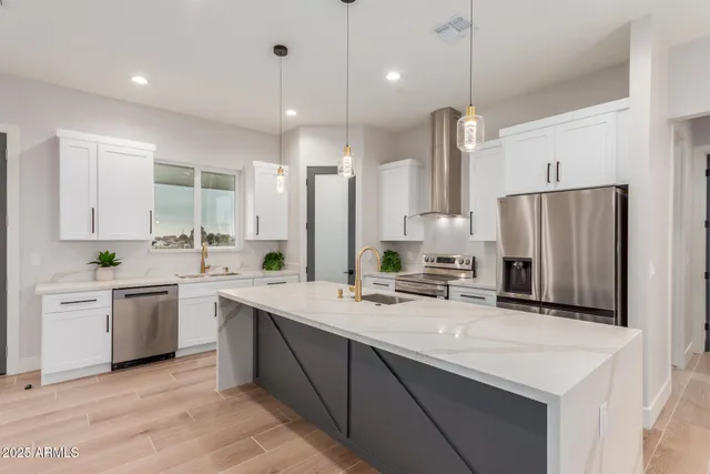 a kitchen with stainless steel appliances granite countertop a sink a stove a refrigerator and island with wooden floor