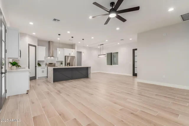 a view of kitchen with kitchen island white cabinets stainless steel appliances and wooden floor