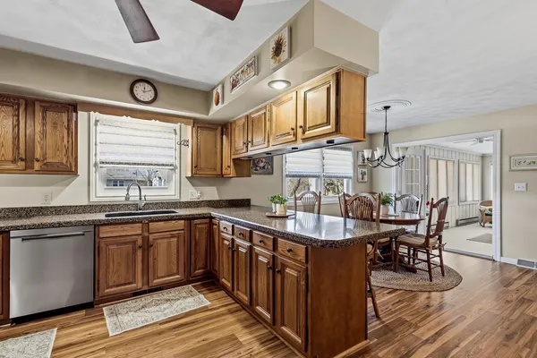a large kitchen with cabinets chairs and wooden floor