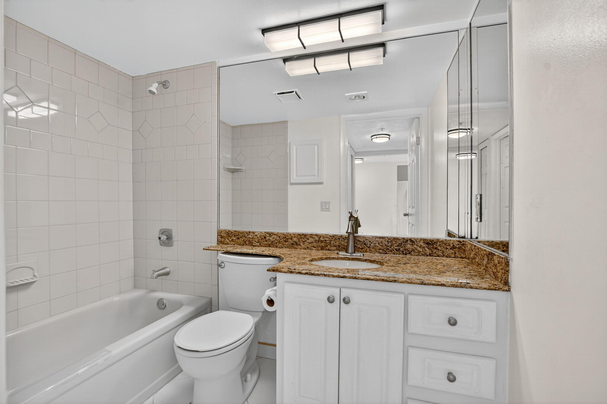 6620 Boca Del Mar Drive, Unit 706 Boca Raton, FL 33433 - Photo 19 of 41 a bathroom with a granite countertop sink a toilet a mirror and bathtub