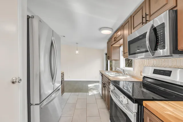 a kitchen with stainless steel appliances granite countertop a refrigerator a stove and a sink