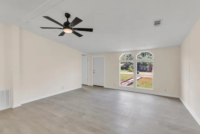 a view of an empty room with window wooden floor