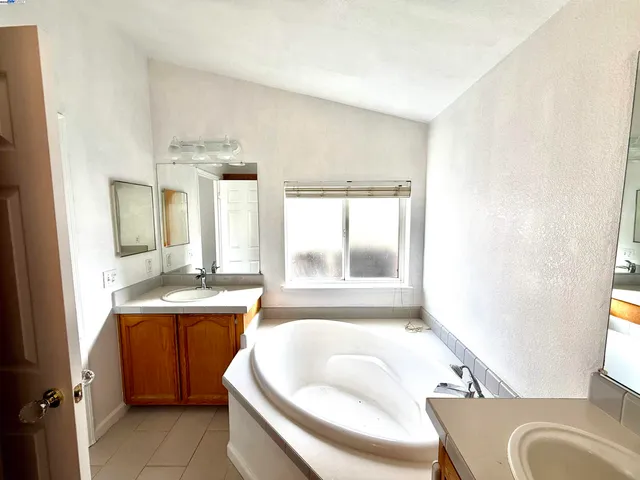 a bathroom with a granite countertop sink mirror bathtub and toilet