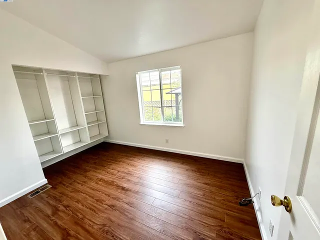 an empty room with wooden floor and window
