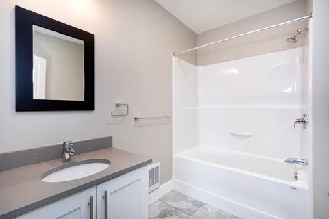 a bathroom with a granite countertop sink mirror and a bathtub