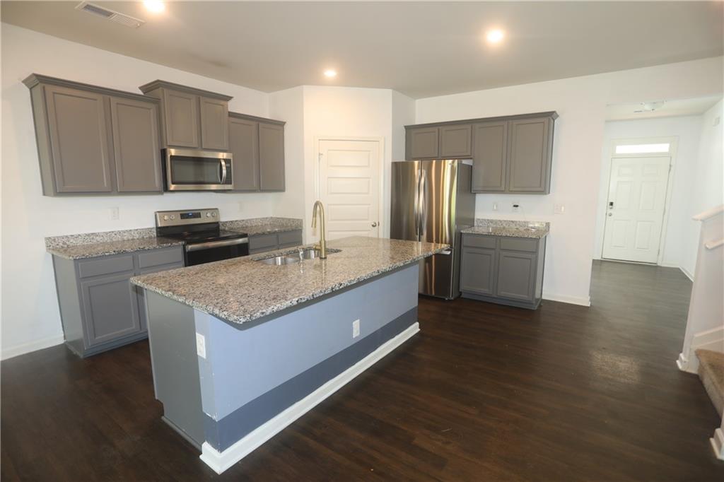 25 Lena Court Covington, GA 30016 - Photo 5 of 36 a kitchen with stainless steel appliances granite countertop a sink stove microwave and refrigerator
