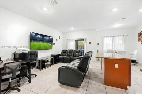 a living room with furniture a flat screen tv and kitchen view