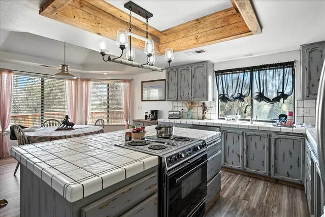 a kitchen with stainless steel appliances granite countertop a stove a refrigerator a dining table and chairs with wooden floor