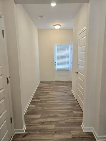 a view of an empty room with wooden floor and a window