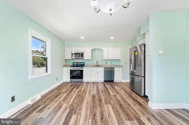 a kitchen with a refrigerator a stove top oven and white walls