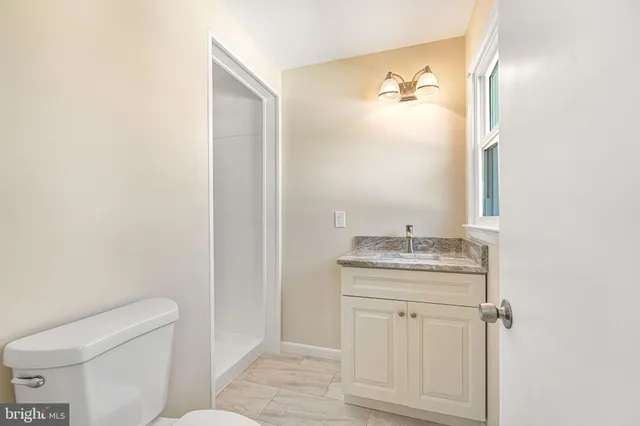 a bathroom with a granite countertop sink and a toilet