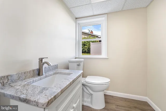 a bathroom with a granite countertop sink and a toilet