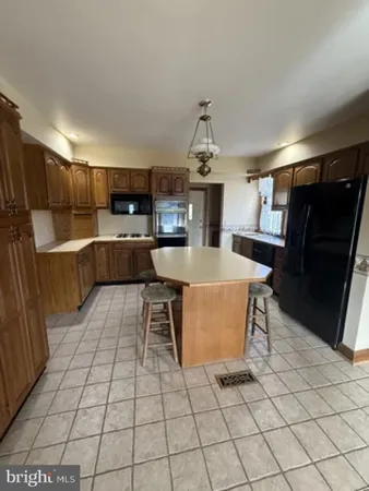 a living room with stainless steel appliances kitchen island granite countertop a refrigerator and a sink