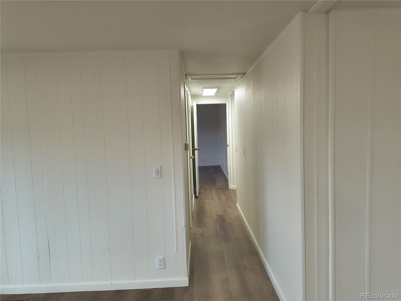 7169 Henry Street Fort Lupton, CO 80621 - Photo 11 of 14 a view of a hallway with wooden floor