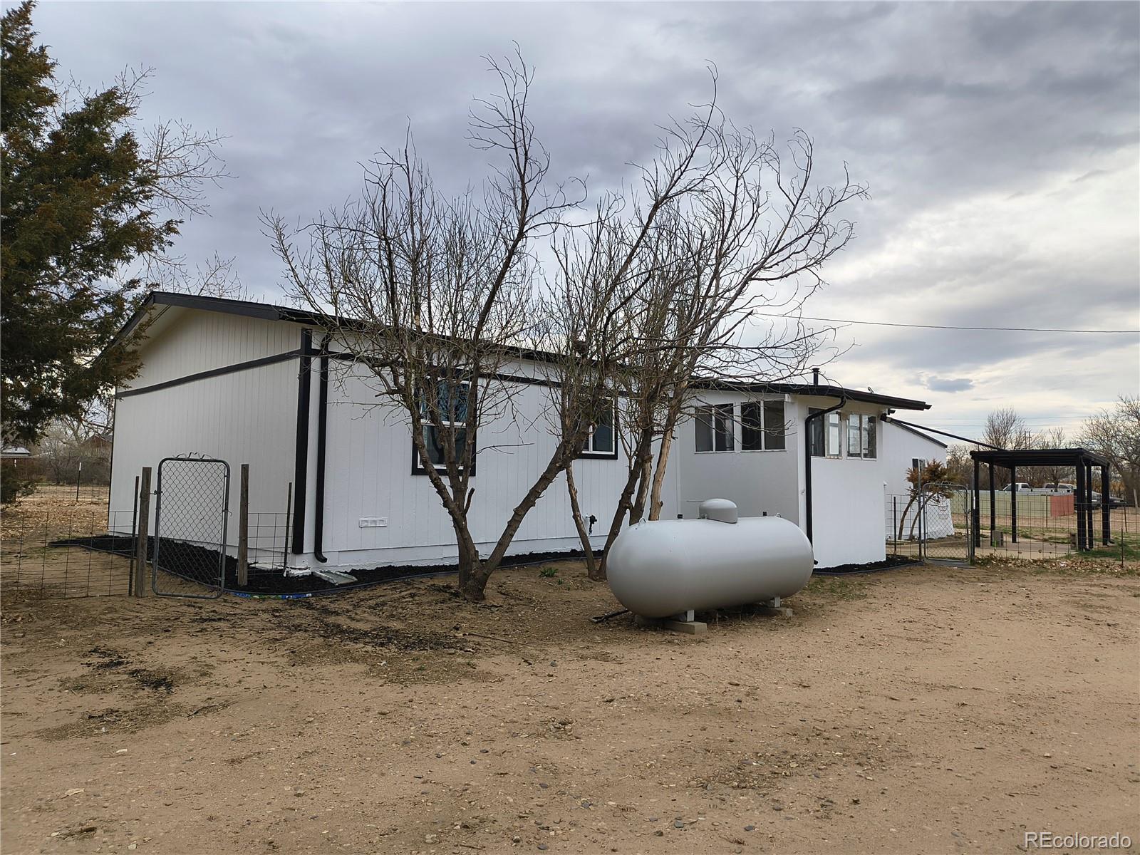 7169 Henry Street Fort Lupton, CO 80621 - Photo 4 of 14 a house with trees in front of it