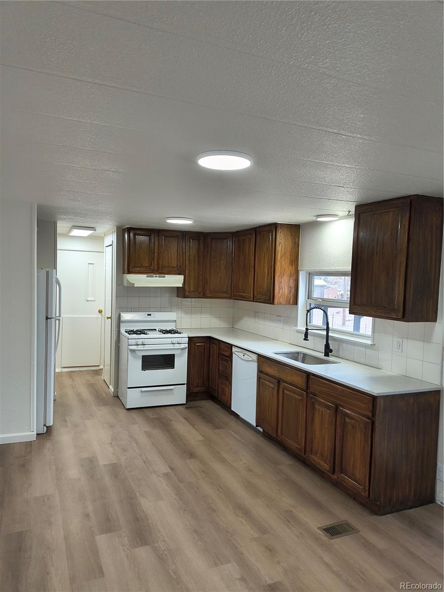 7169 Henry Street Fort Lupton, CO 80621 - Photo 7 of 14 a large kitchen with stainless steel appliances granite countertop a stove a sink dishwasher and a oven