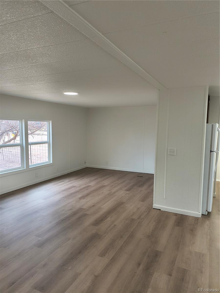 7169 Henry Street Fort Lupton, CO 80621 - Photo 8 of 14 an empty room with wooden floor and windows