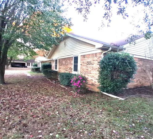 a front view of a house with a yard and a large tree