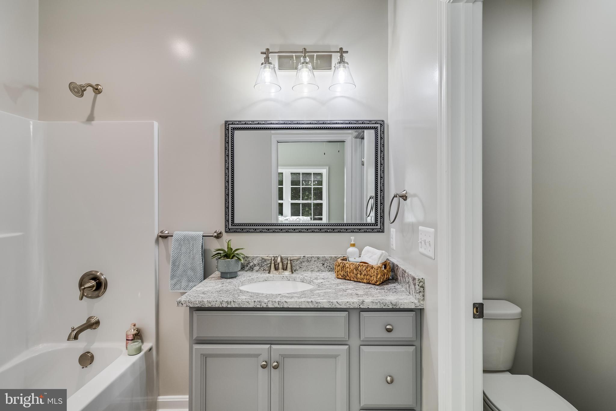 21183 Abell Road Avenue, MD 20609 - Photo 12 of 36 a bathroom with a granite countertop sink a toilet a mirror and bathtub