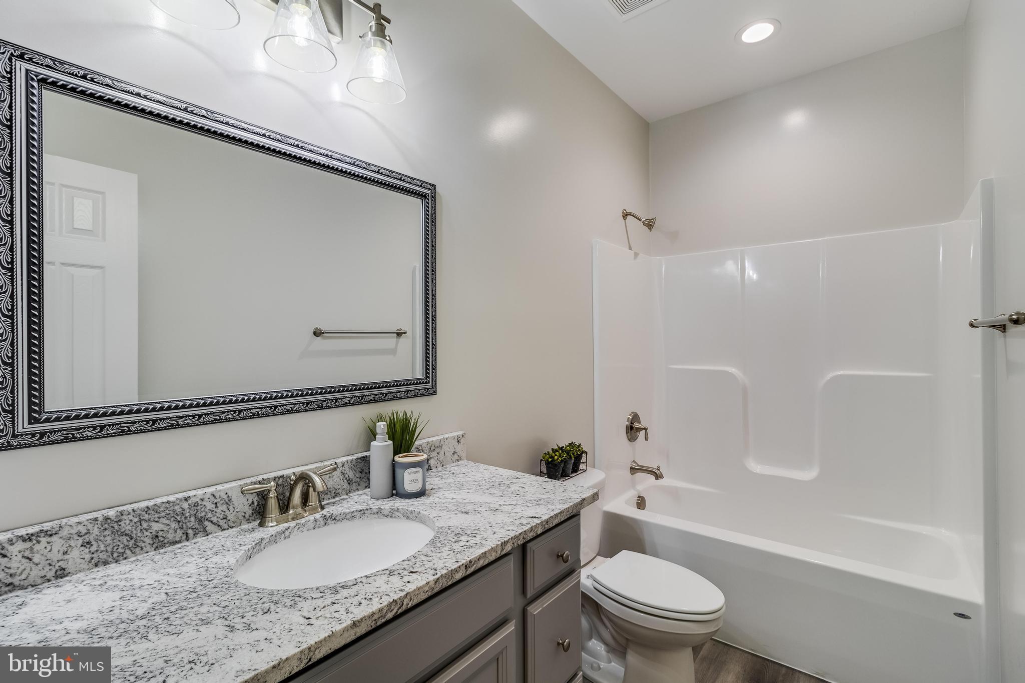 21183 Abell Road Avenue, MD 20609 - Photo 19 of 36 a bathroom with a granite countertop toilet a sink and a mirror