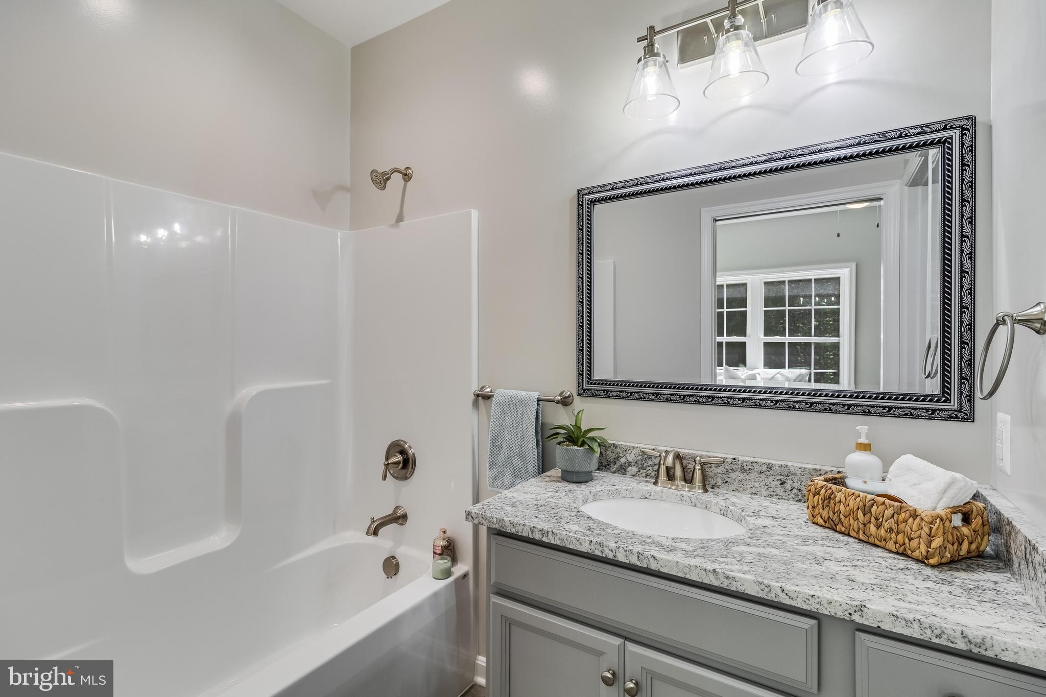 21183 Abell Road Avenue, MD 20609 - Photo 24 of 36 a bathroom with a granite countertop sink mirror and a bathtub