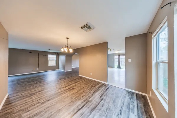 a view of an empty room with window and wooden floor