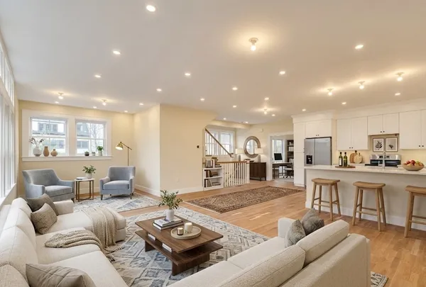 a living room with furniture kitchen view and a wooden floor