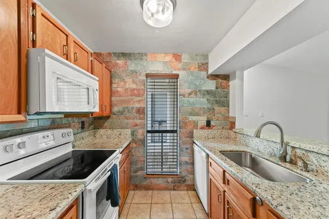 a kitchen with stainless steel appliances granite countertop a sink stove and cabinets