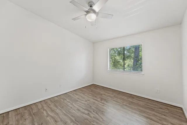 an empty room with a window and a fan
