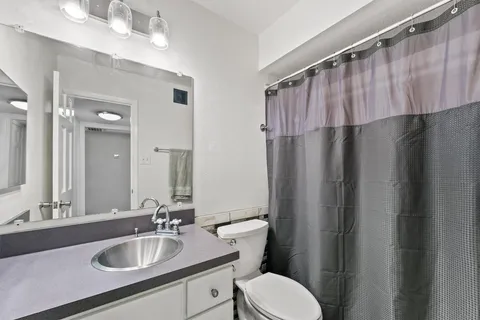 a bathroom with a sink a toilet a mirror and shower curtain