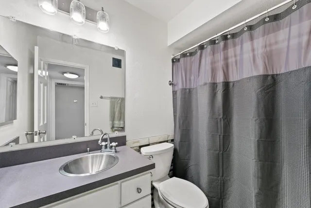 a bathroom with a sink a toilet a mirror and shower curtain