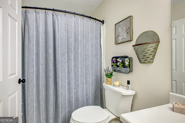 a white toilet sitting next to a bathroom sink and a shower curtain