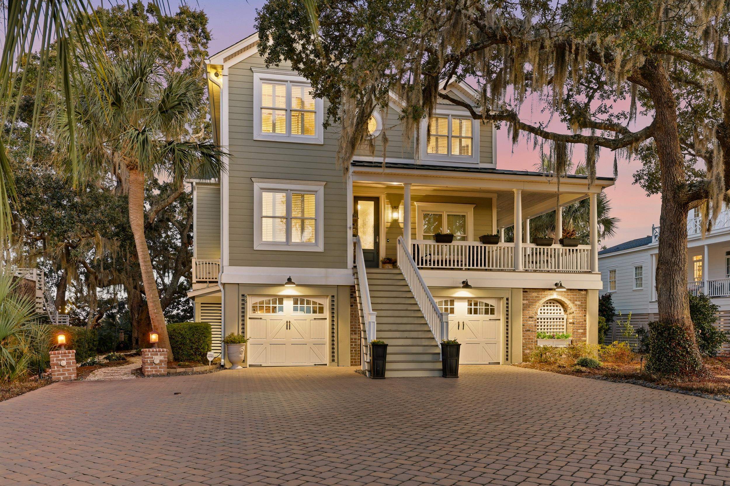 Coastal inspired home featuring a porch, stairway, an attached garage, and decorative driveway