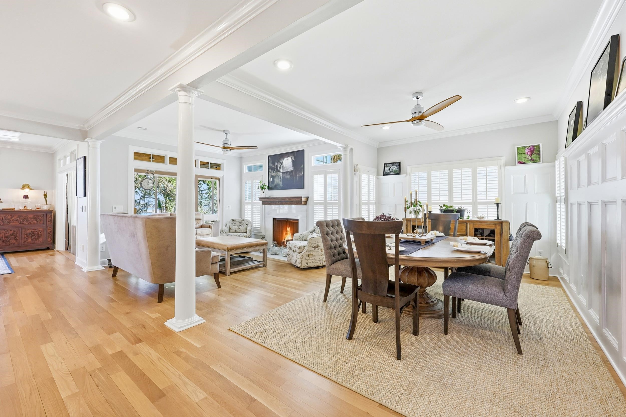 46 High Hammock Way Pawleys Island, SC 29585 - Photo 6 of 40 Dining area with ornate columns, a ceiling fan, ornamental molding, light wood-style flooring, and a warm lit fireplace