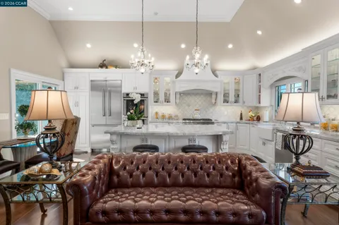 a living room with furniture kitchen view and a chandelier