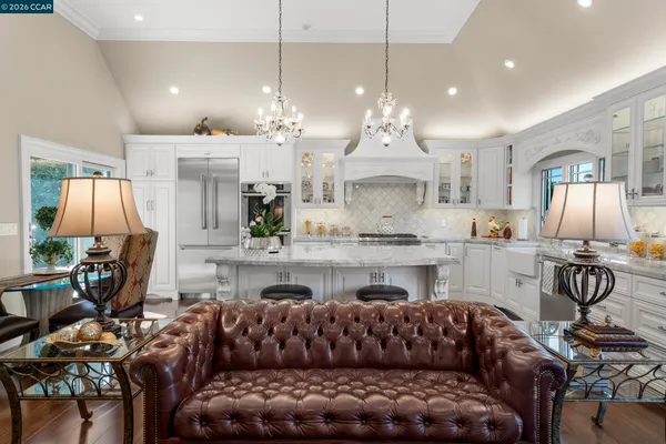 a living room with furniture kitchen view and a chandelier