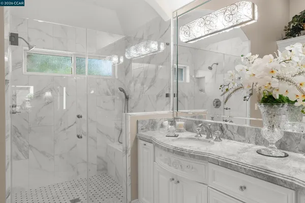 a bathroom with a granite countertop double vanity sink mirror and shower