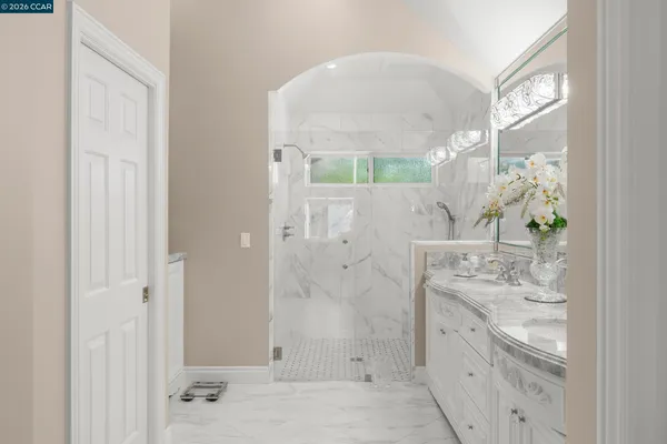 a bathroom with a granite countertop sink a mirror and shower