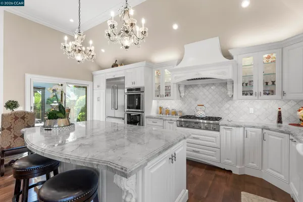 a kitchen with stainless steel appliances granite countertop a sink a stove a dining table and chairs