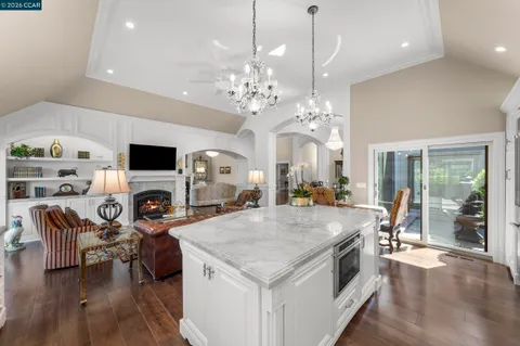 a open kitchen with stainless steel appliances granite countertop a stove oven a dining table and chairs with wooden floor