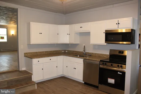a kitchen with granite countertop a stove and a microwave