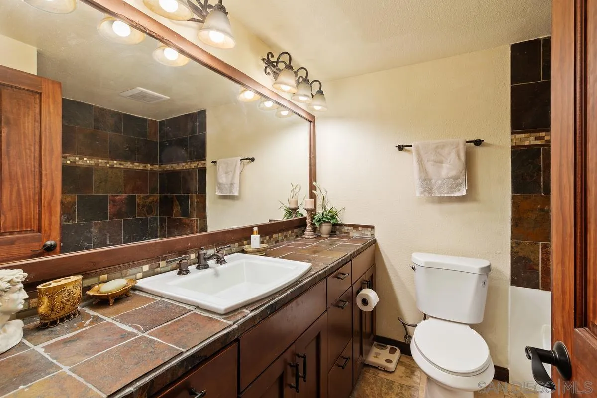 17442 Port Marnock Drive Poway, CA 92064 - Photo 23 of 28 a bathroom with a granite countertop toilet a sink and a mirror