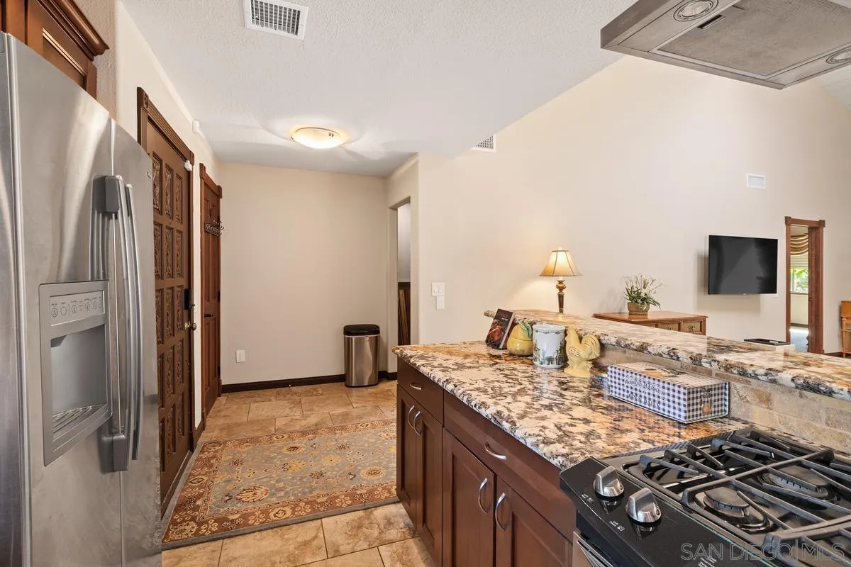 17442 Port Marnock Drive Poway, CA 92064 - Photo 8 of 28 a kitchen with kitchen island granite countertop a stove and a refrigerator