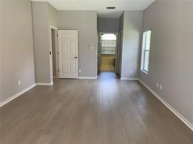 an empty room with wooden floor and a mirror