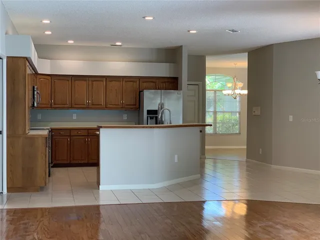 a kitchen with stainless steel appliances granite countertop a refrigerator a sink dishwasher a stove and oven with wooden floor